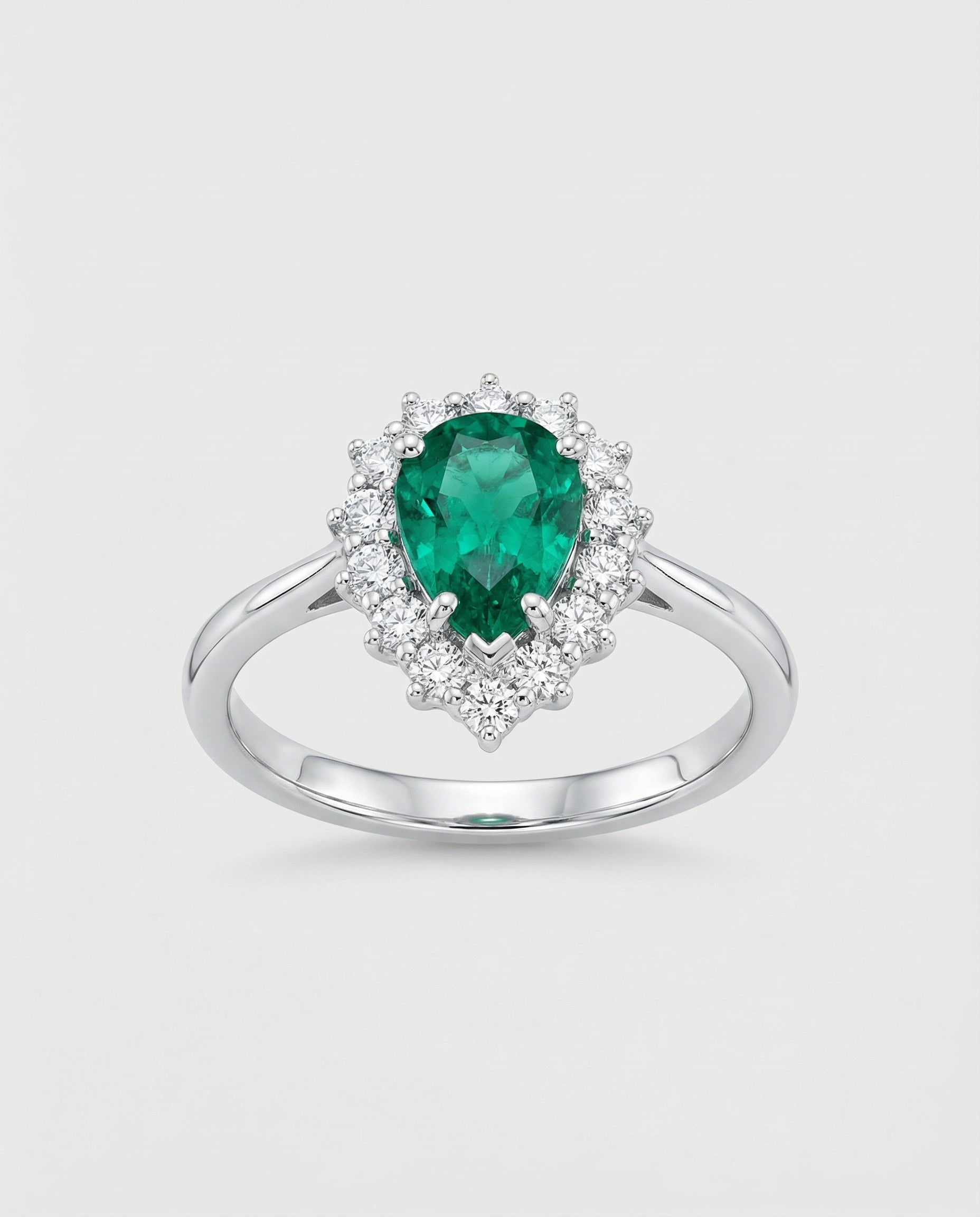 Ring with a green emerald gemstone and diamond accents on a light gray background