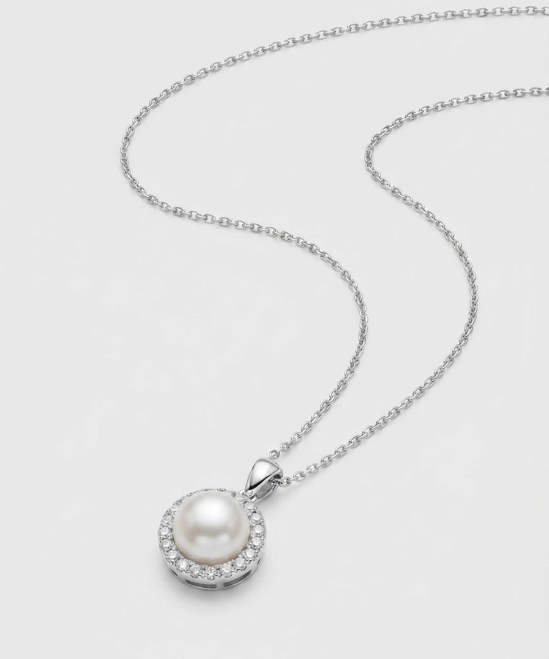 Pearl necklace with white-gold chain on a light gray background