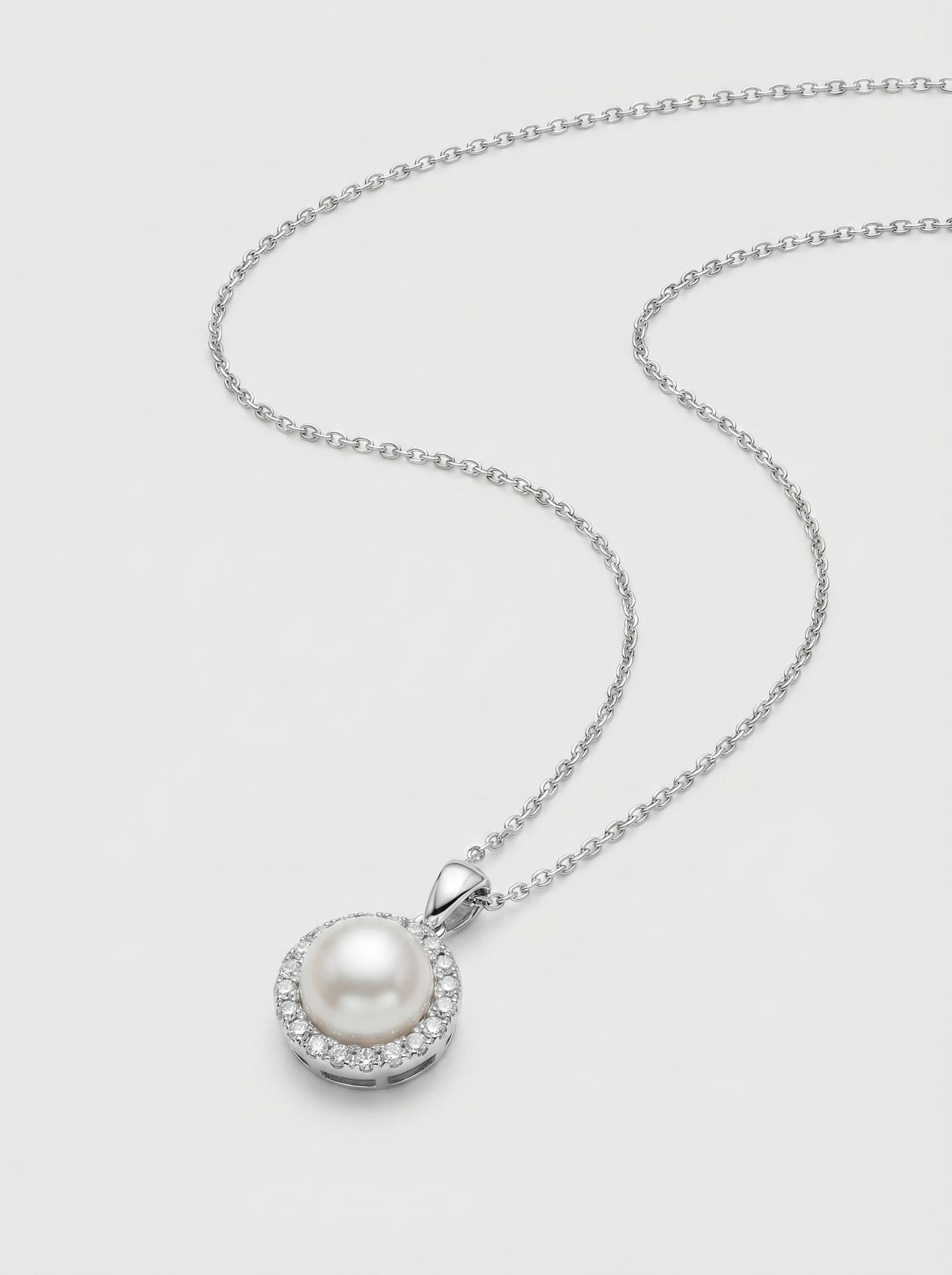 Pearl necklace with white-gold chain on a light gray background