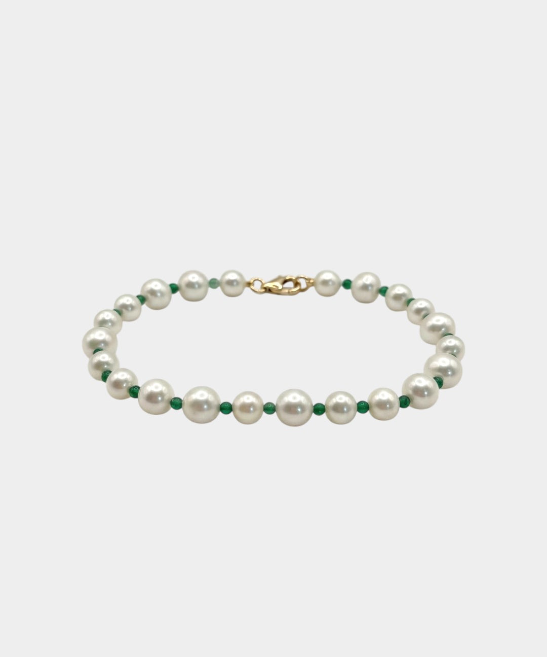 Pearl necklace with green beads on a light gray background