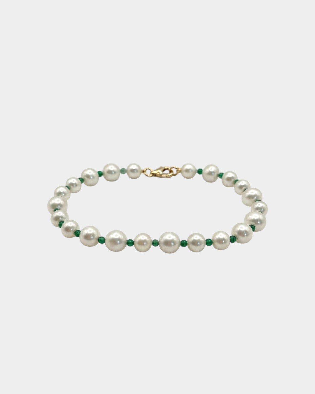 Pearl necklace with green beads on a light gray background