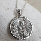 Silver angel pendant necklace on a textured surface