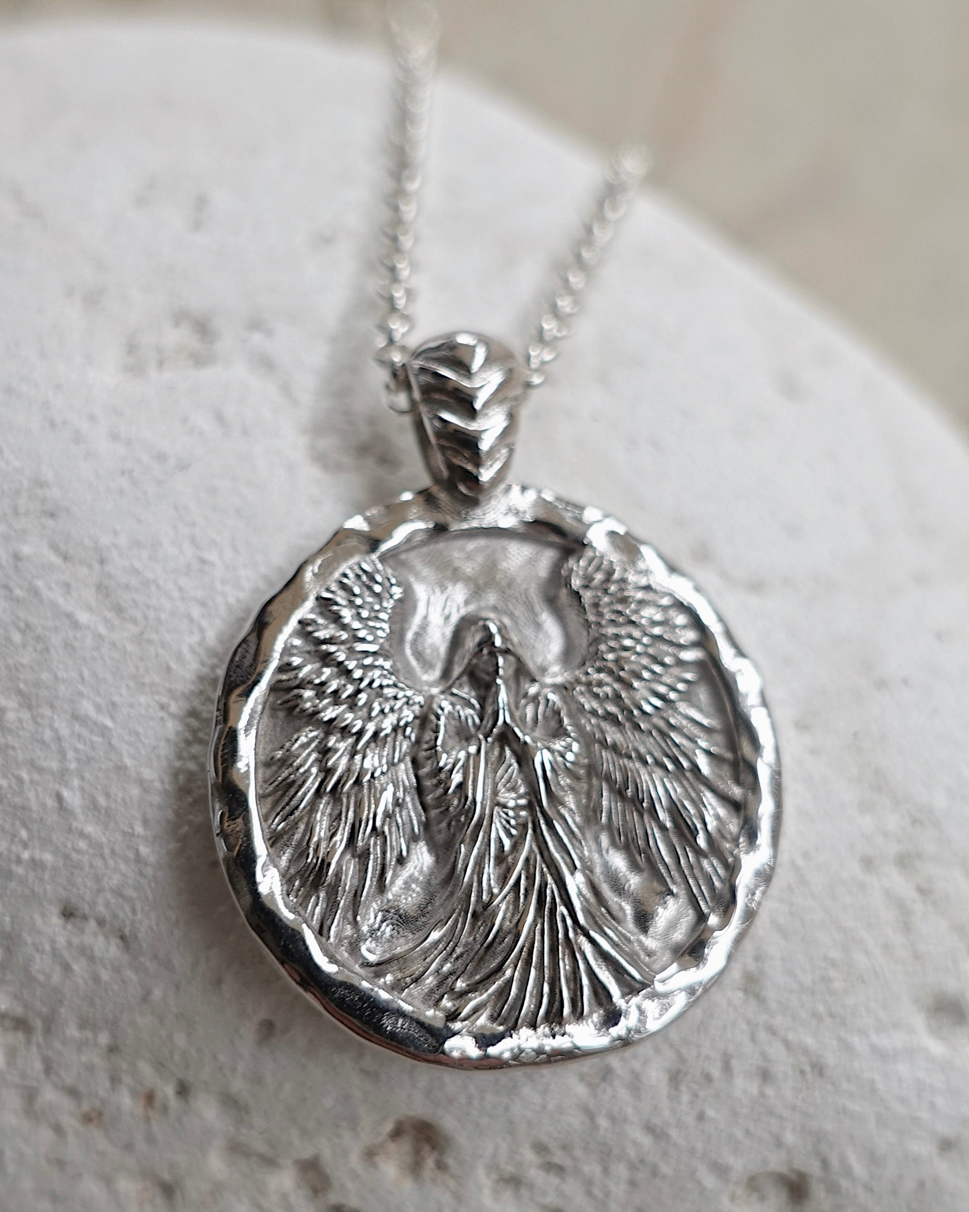 Silver angel pendant necklace on a textured surface