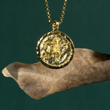Gold necklace with a coin pendant featuring a Spartan soldier on a dark green background