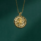 Gold necklace with a round pendant on a dark green background