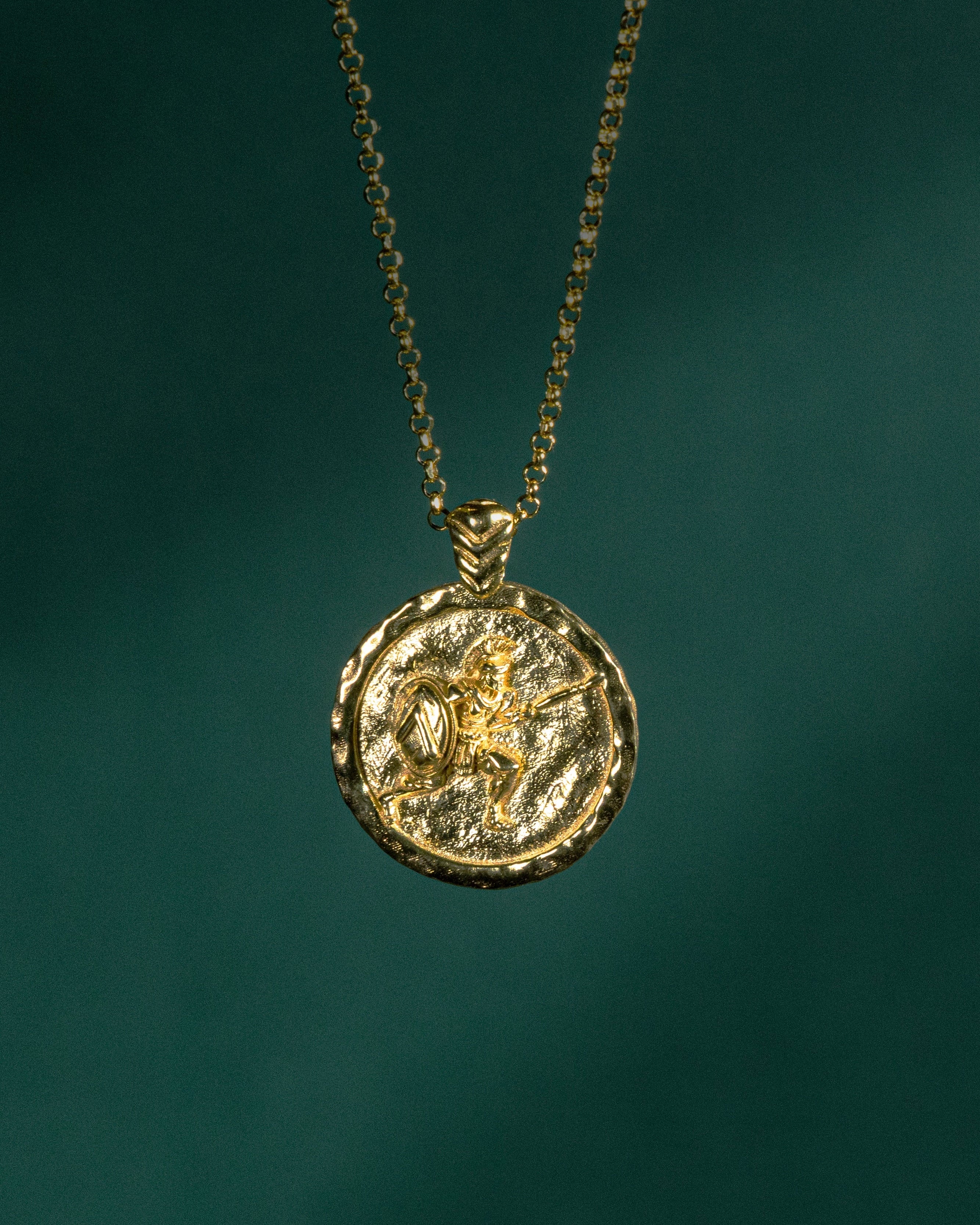 Gold necklace with a round pendant on a dark green background