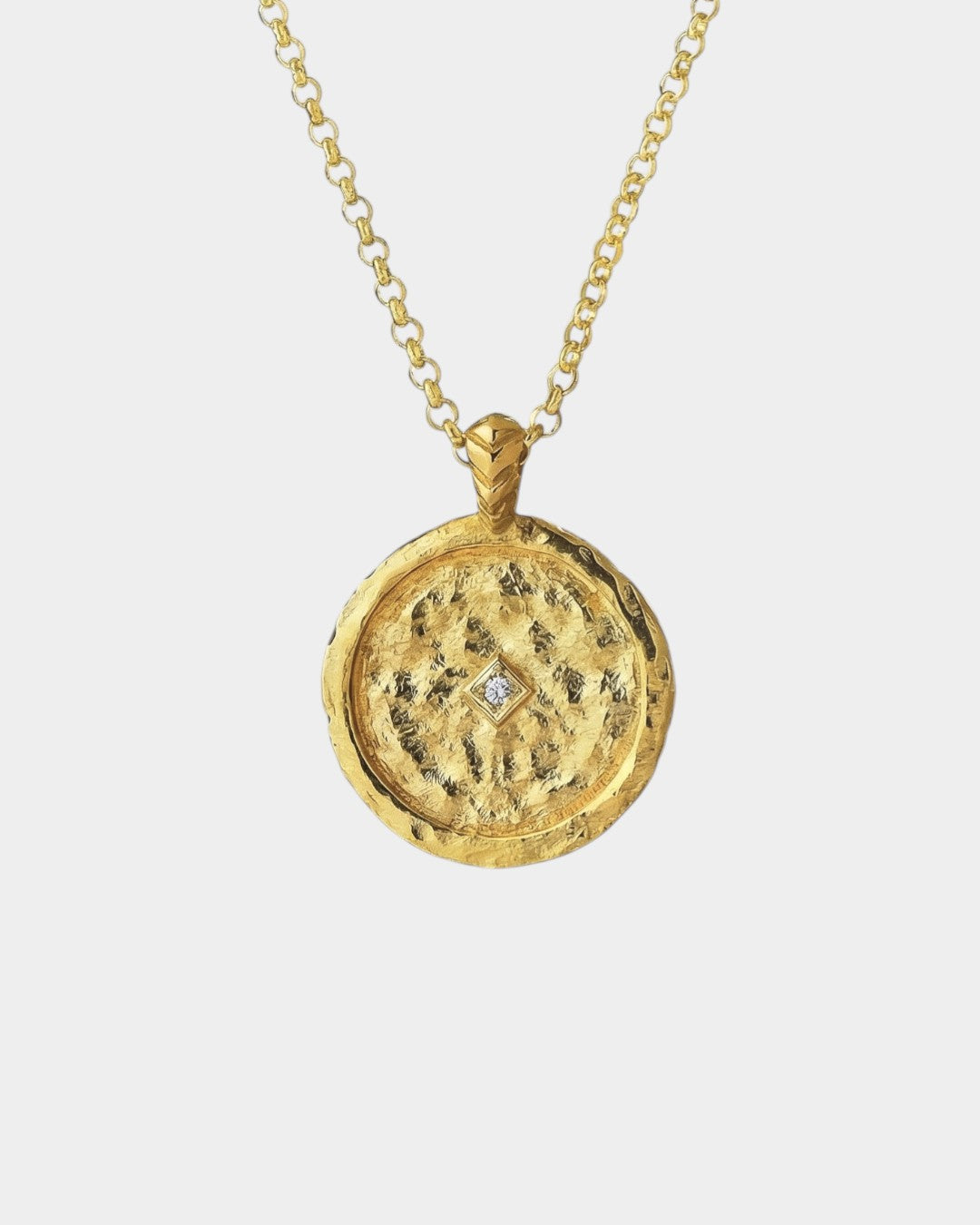 Gold necklace with a round pendant with a zircon on a white background
