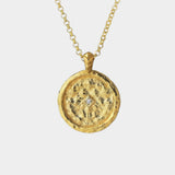 Gold necklace with a round pendant with a zircon on a white background