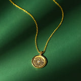 Gold necklace with a pendant and a zircon on a green fabric background
