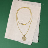 Gold necklace with a pendant and a zircon on a white fabric background