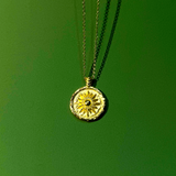 Necklace with a round pendant with sun motif on a green background