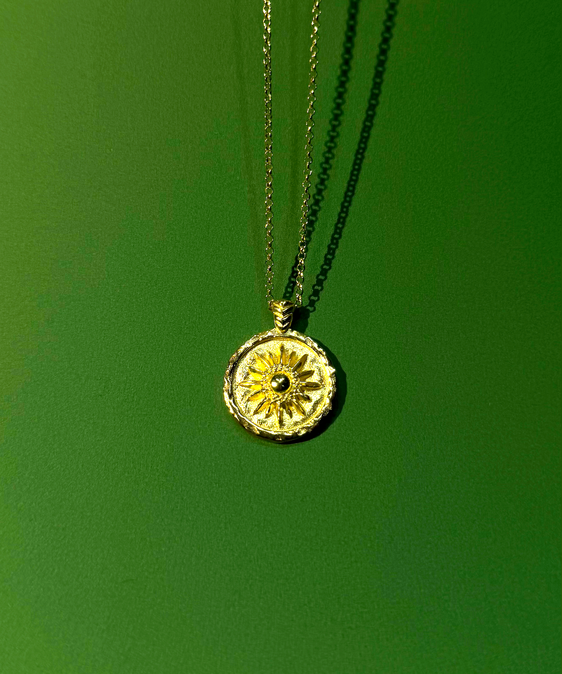 Necklace with a round pendant with sun motif on a green background