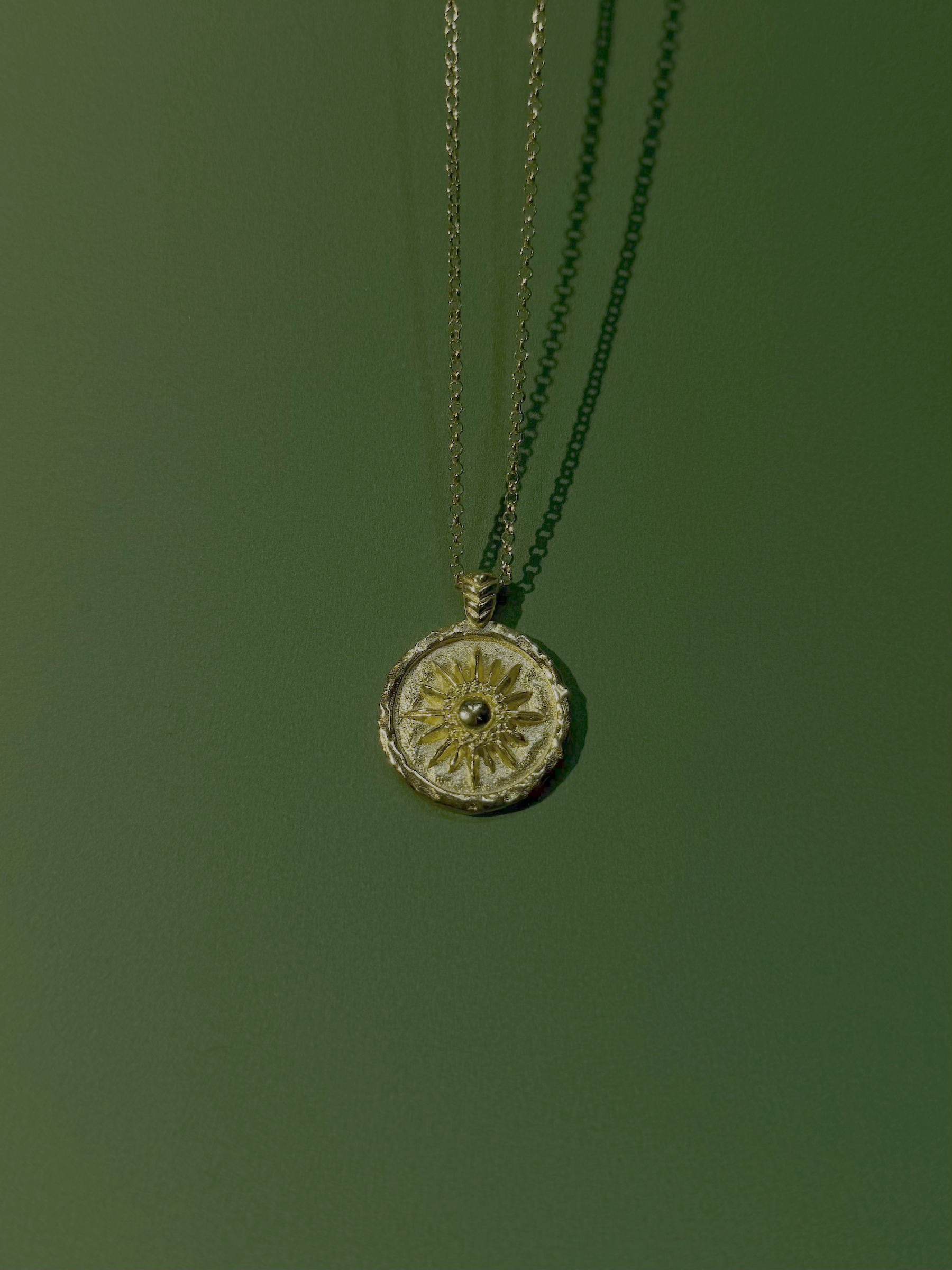 Necklace with a round pendant with sun motif on a green background