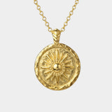Gold necklace with a sun-shaped pendant on a white background