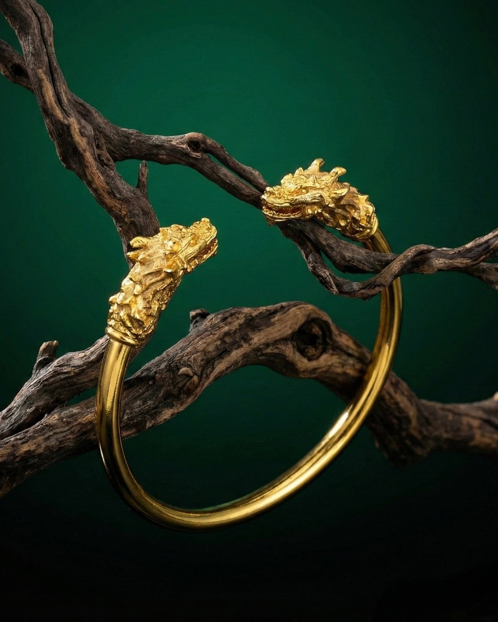 Gold bracelet with dragon head designs on a dark background