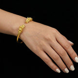 Gold bracelet on a wrist with a black background