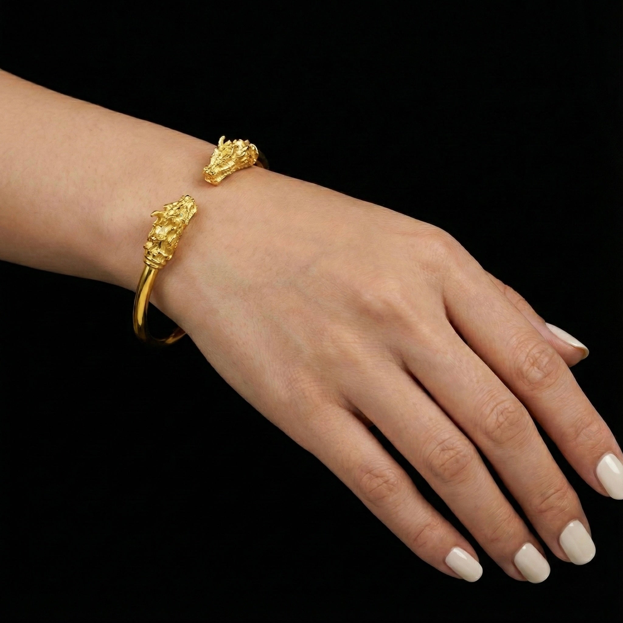 Gold bracelet on a wrist with a black background