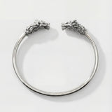 Silver bracelet with dragon head designs on a white background