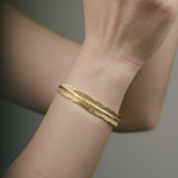 Gold bracelet on a wrist with a neutral background