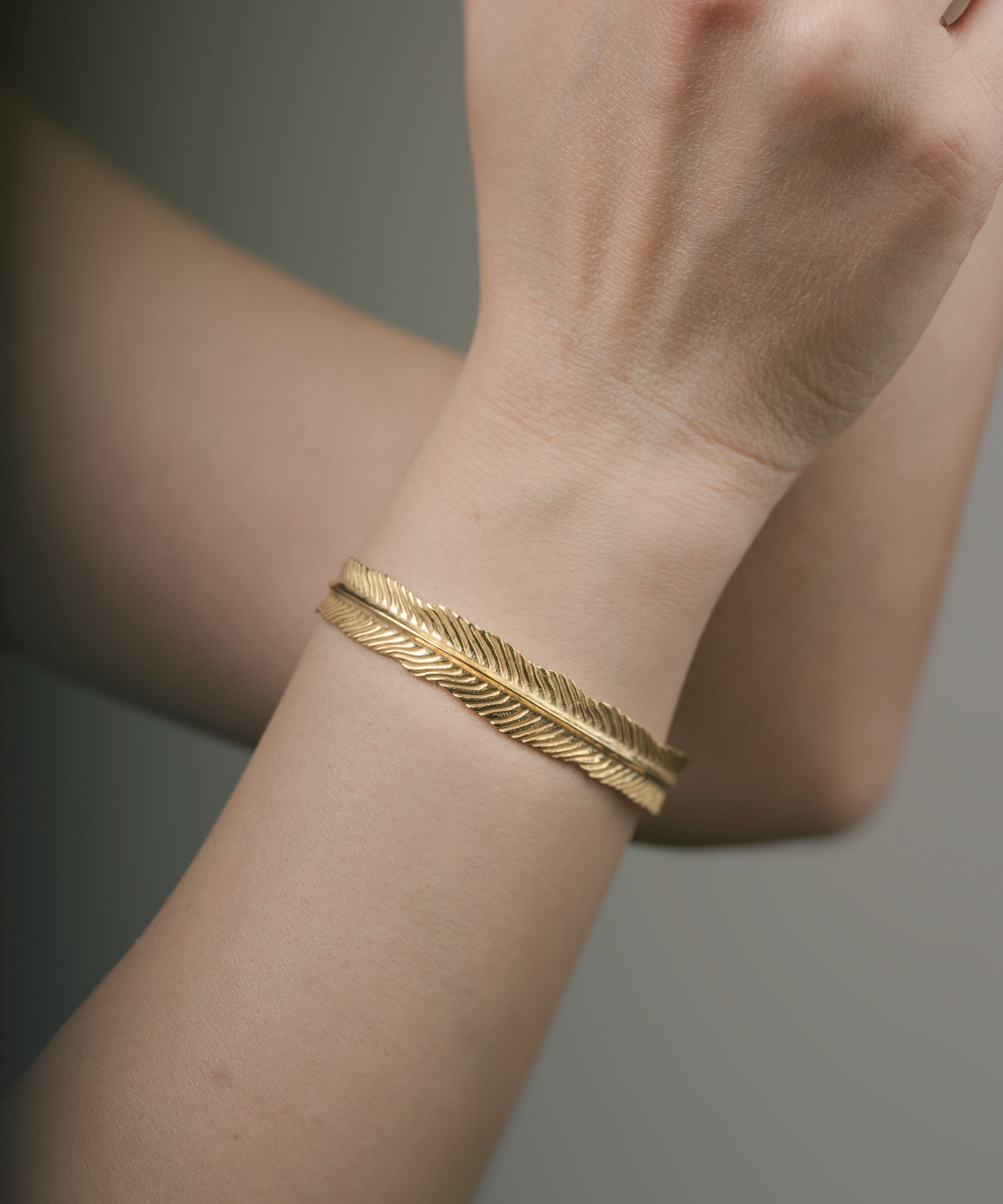 Gold bracelet on a wrist with a neutral background