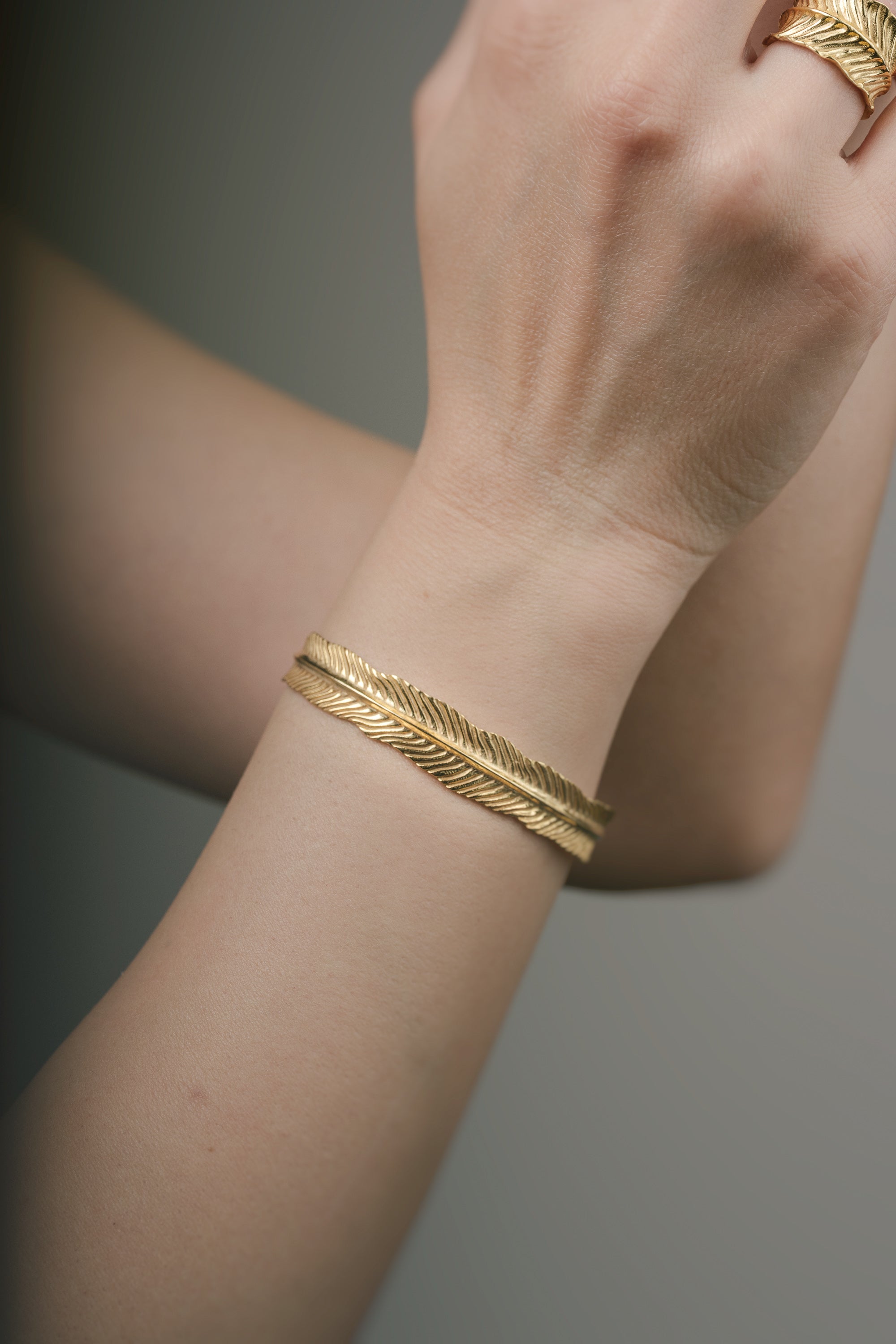 Gold bracelet on a wrist with a neutral background