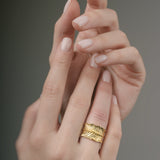 Gold ring on a finger against a neutral background