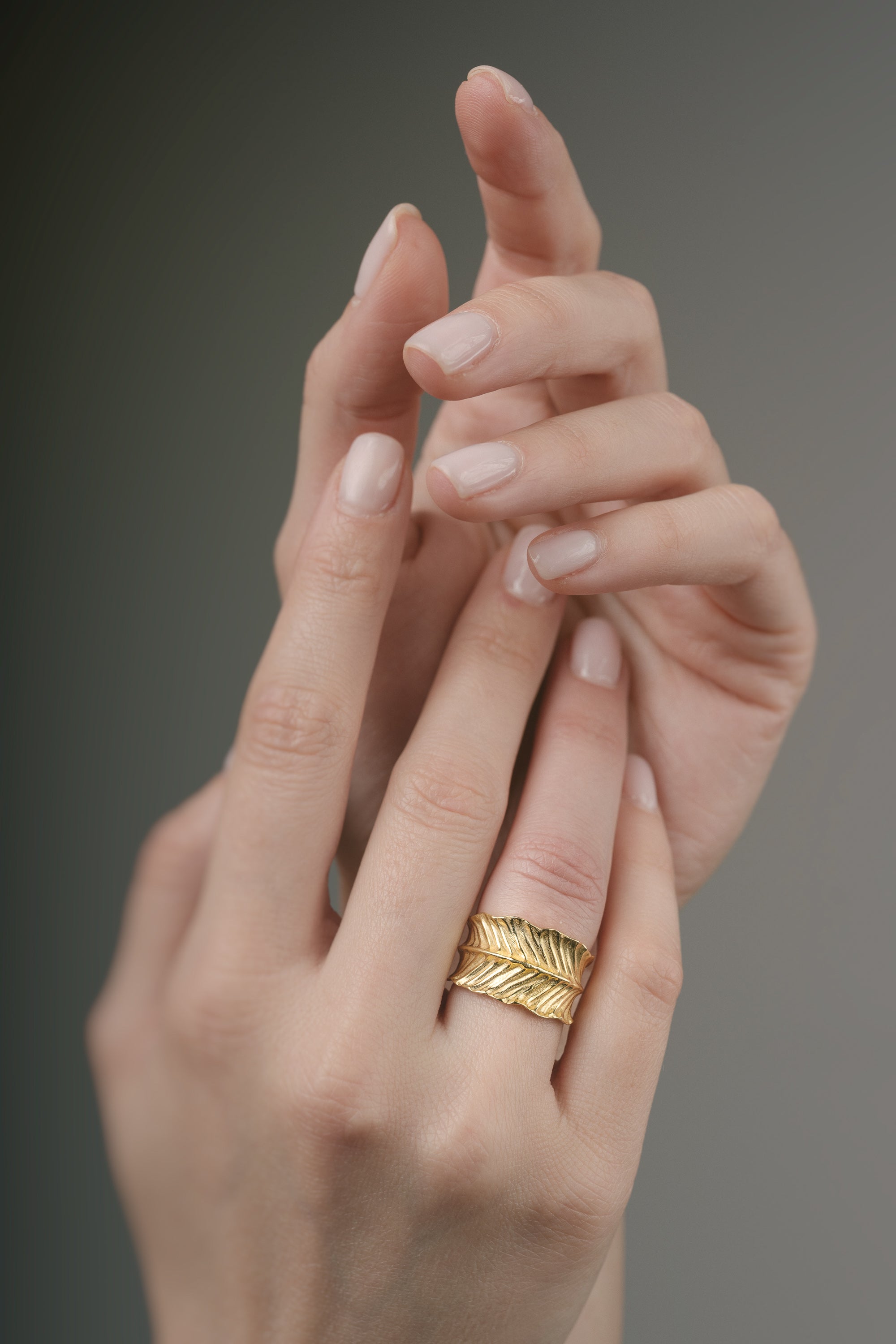 Gold ring on a finger against a neutral background