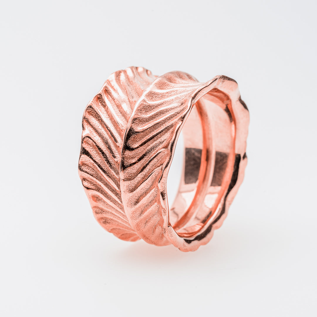 Rose gold ring with dragon's eye design on a light gray background
