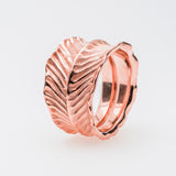 Rose gold ring with dragon's eye design on a light gray background