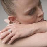 Close-up of a woman's hand with a ring and bracelet on a neutral background