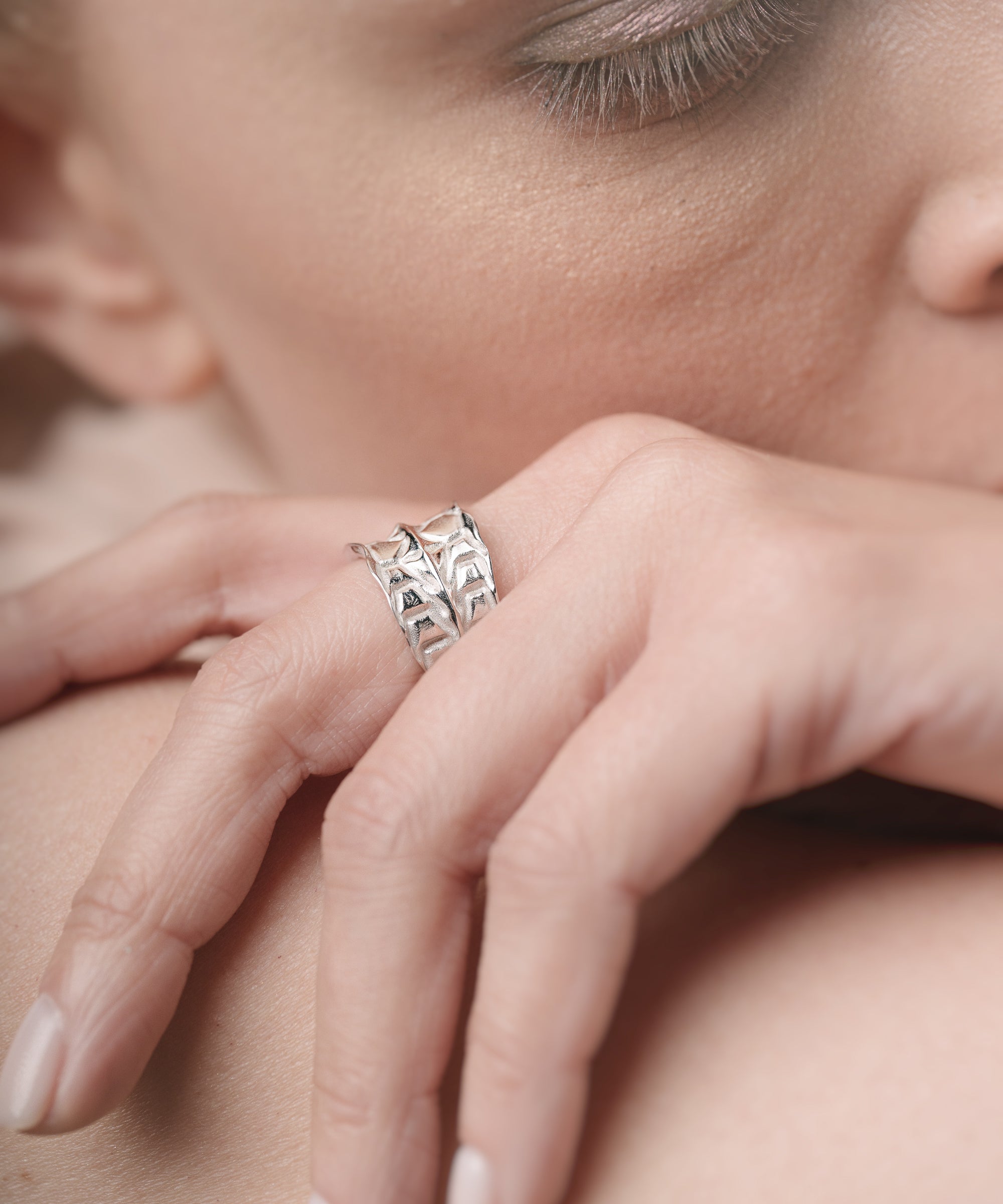 Close-up of a hand wearing a silver ring on a blurred background