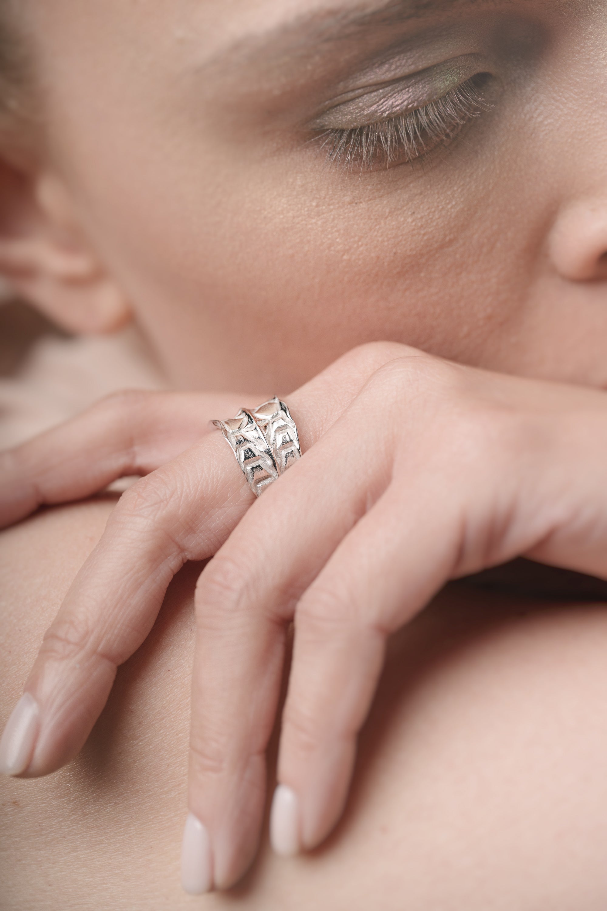 Close-up of a hand wearing a silver ring on a blurred background