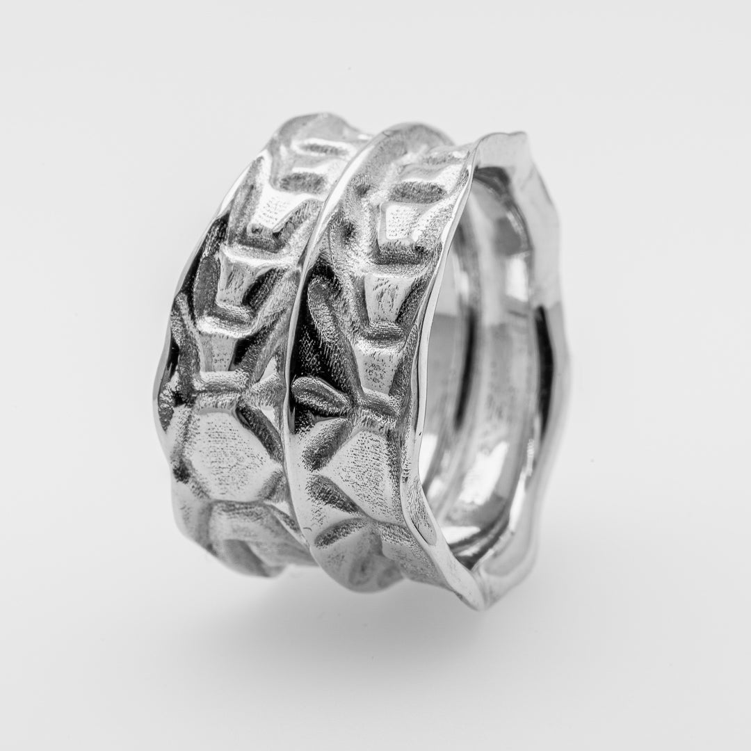 Silver ring with intricate design on a light gray background