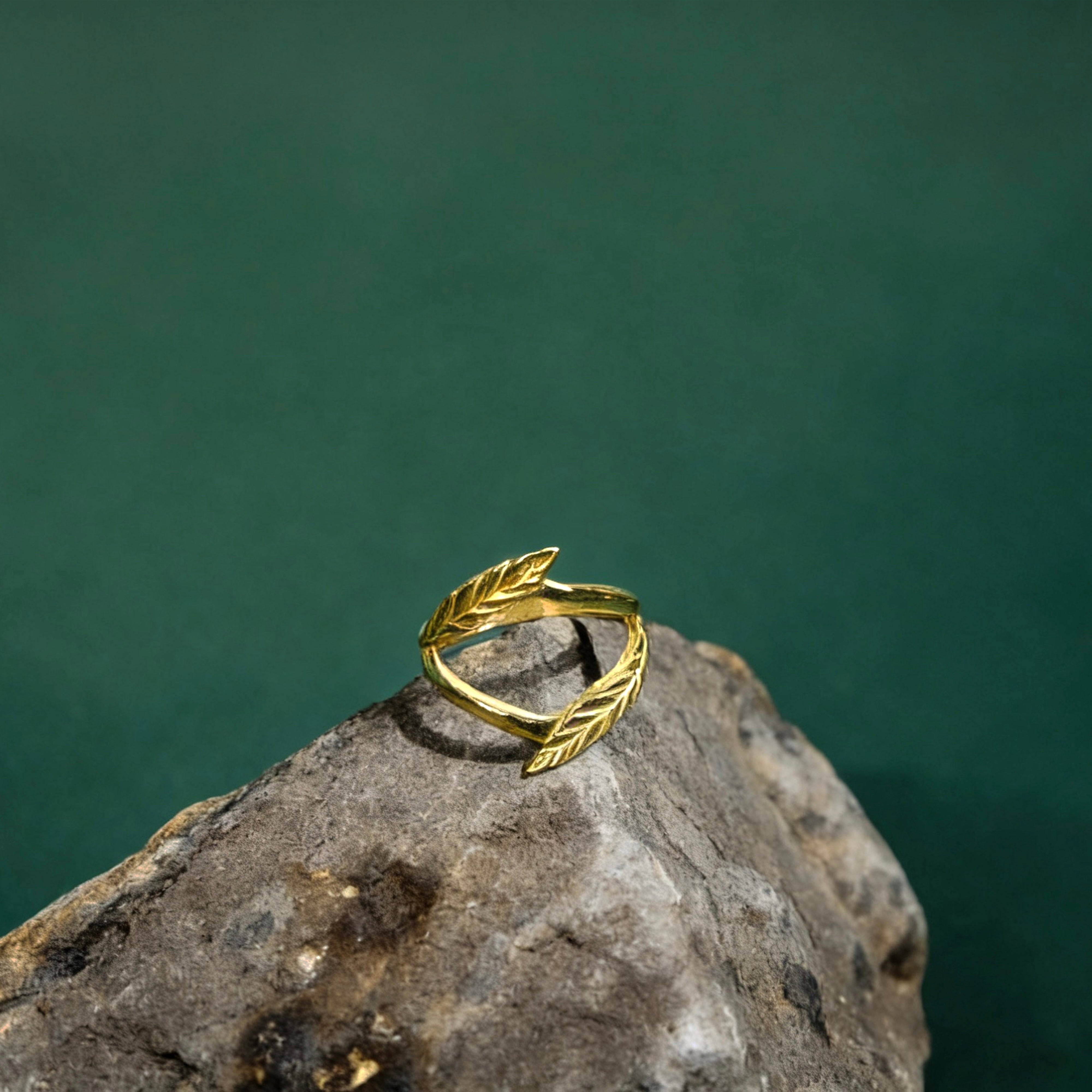 Gold leaf-shaped ring on a rock with a green background