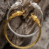 Gold and silver bracelets with elephant designs on a wooden surface
