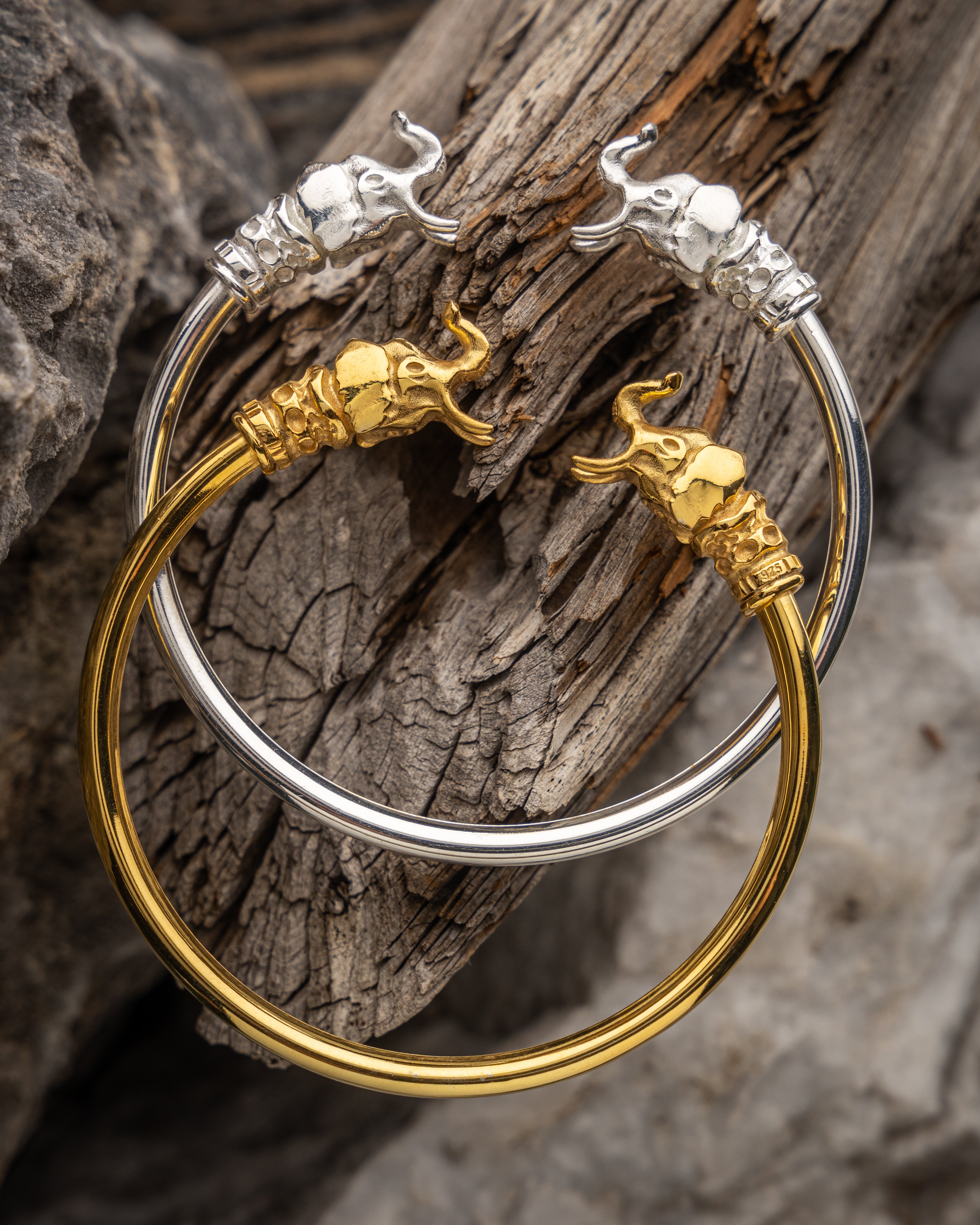 Gold and silver bracelets with elephant designs on a wooden surface
