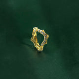 Gold ring with small stones on a dark green background