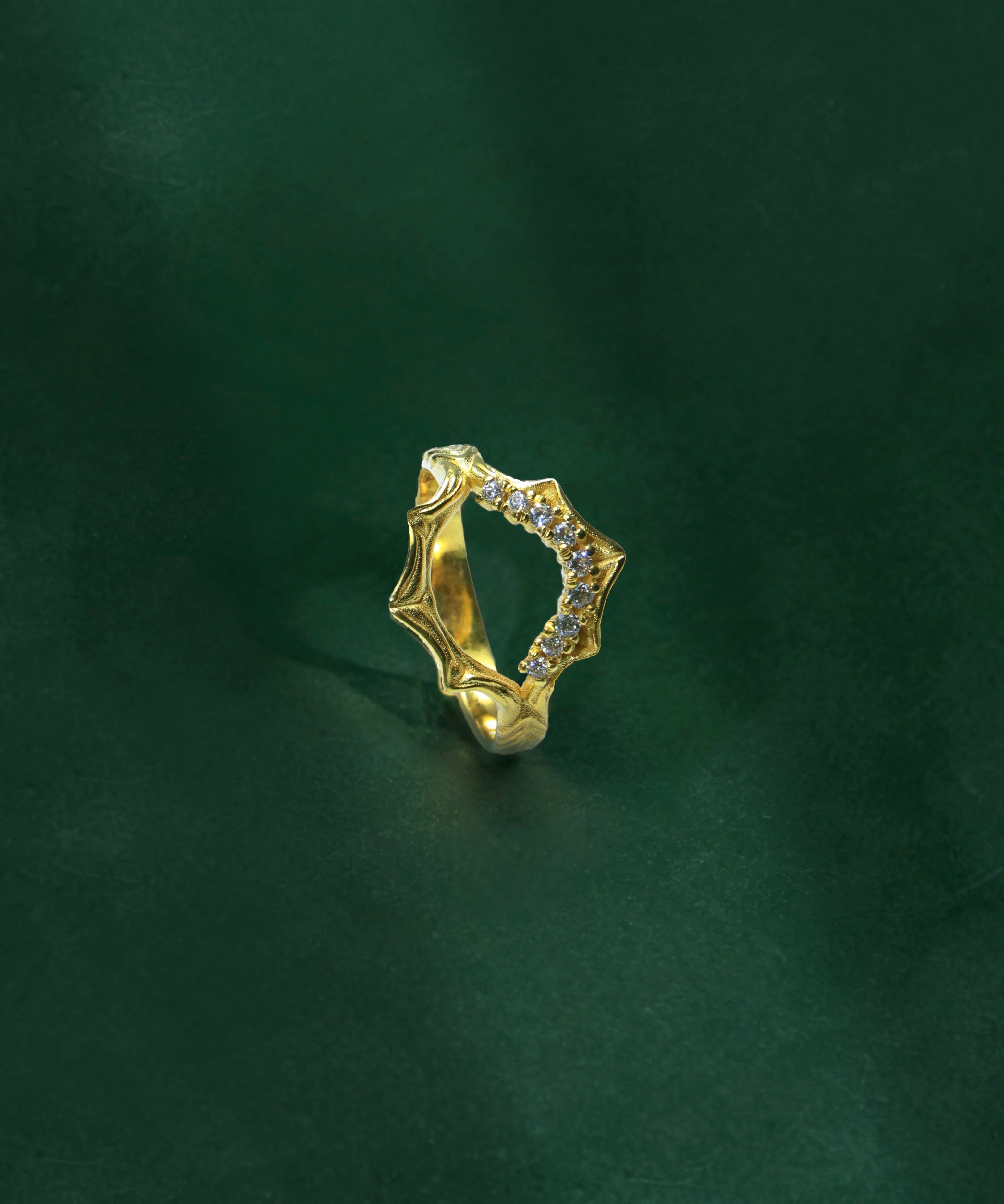 Gold ring with small stones on a dark green background