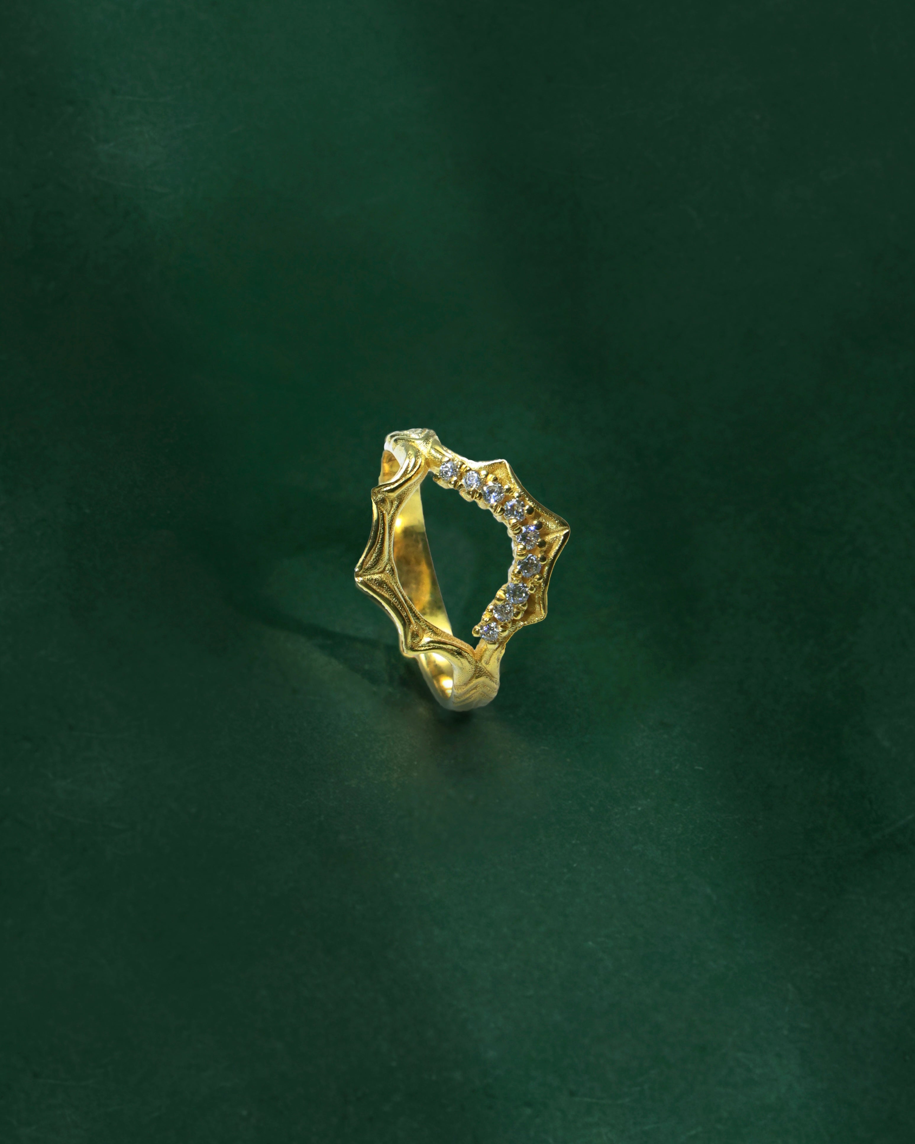 Gold ring with small stones on a dark green background