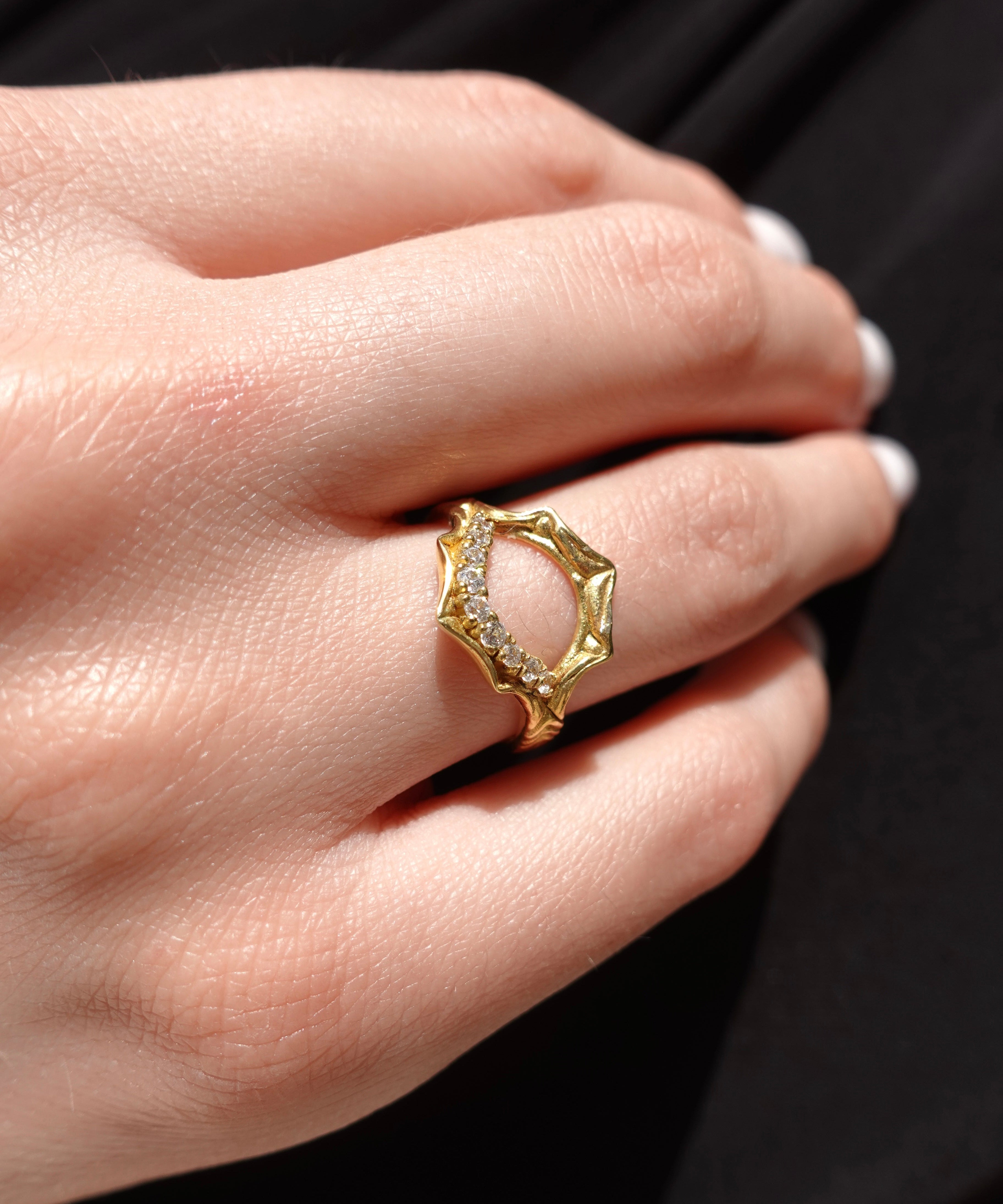 Gold ring with a diamond on a hand against a black background