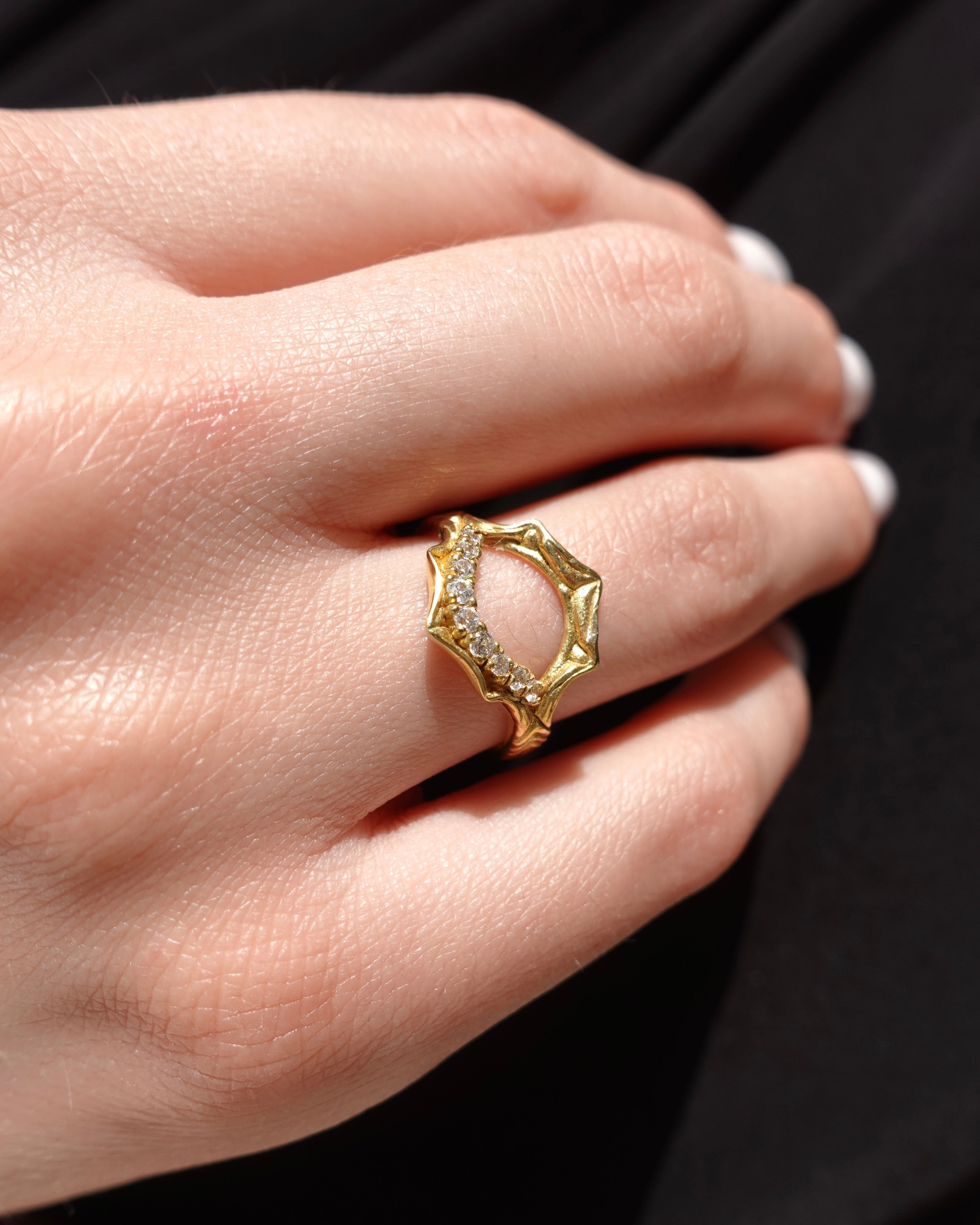 Gold ring with a diamond on a hand against a black background