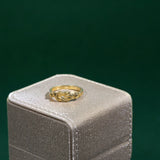 Gold Hercules knot ring on a gray jewelry box with a green background