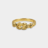 Gold ring with a Hercules knot design on a white background