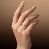 Hand wearing a gold infinity ring on a brown background