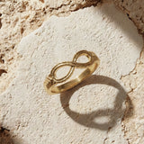 Gold infinity ring on a textured stone surface