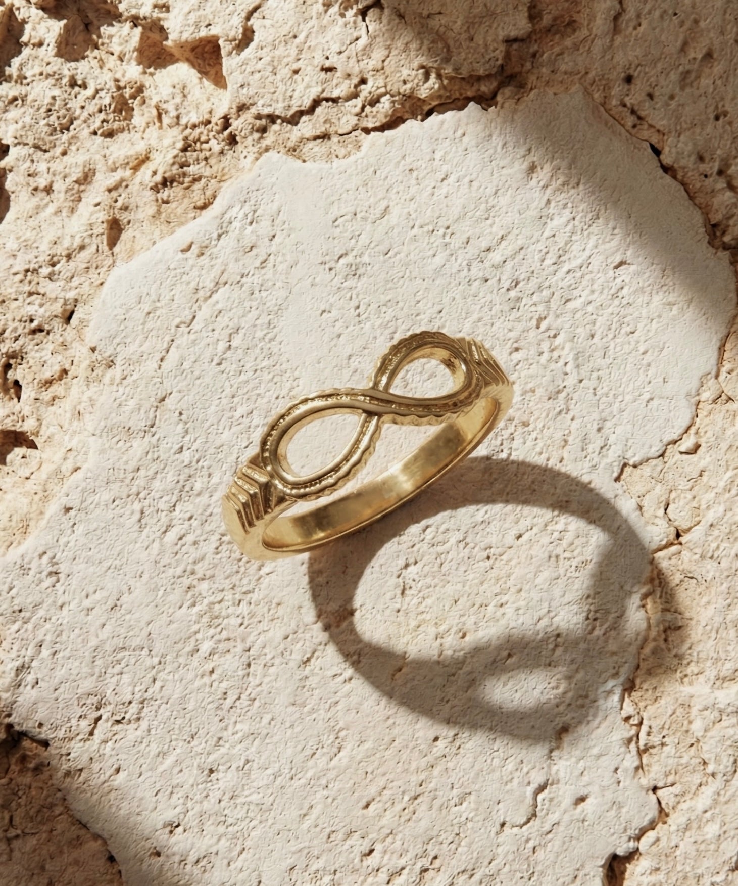 Gold infinity ring on a textured stone surface