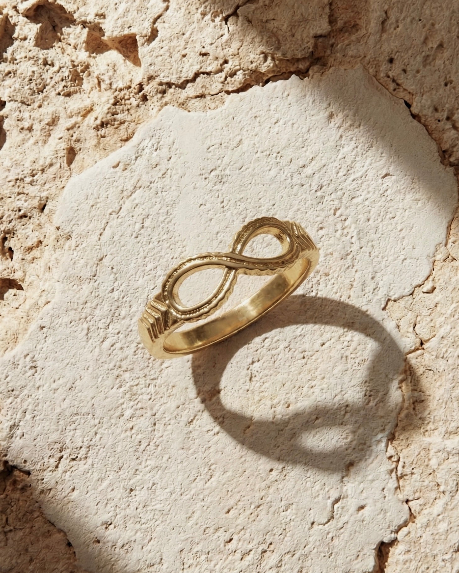 Gold infinity ring on a textured stone surface