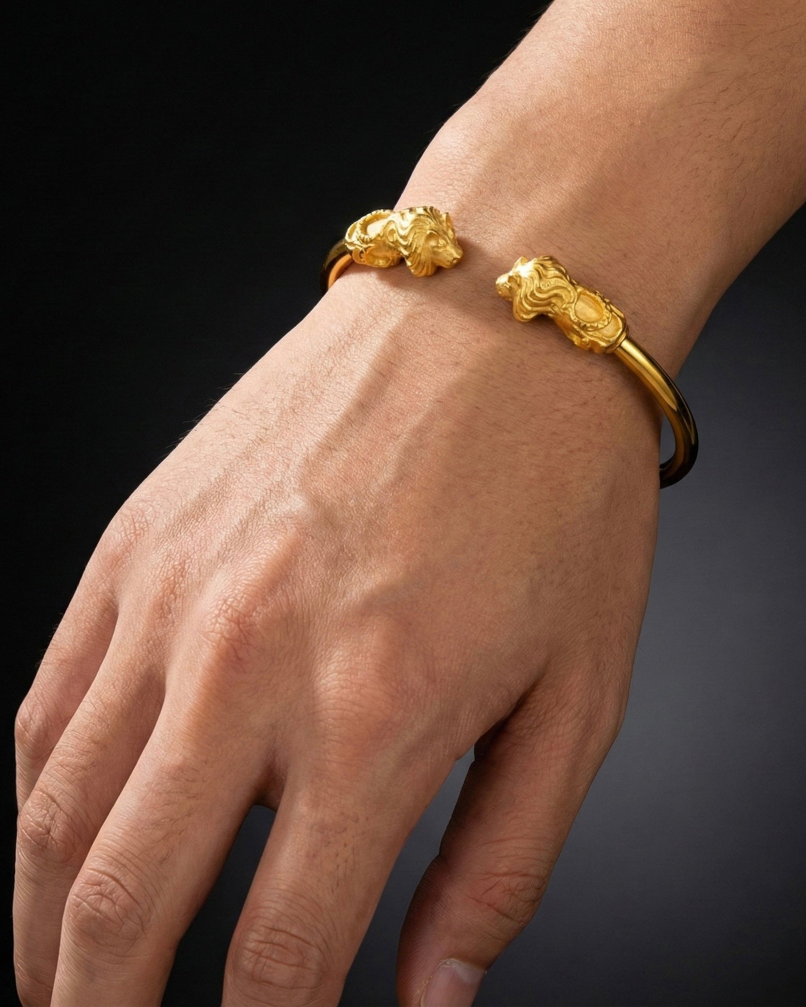 Gold bracelet on a wrist against a dark background