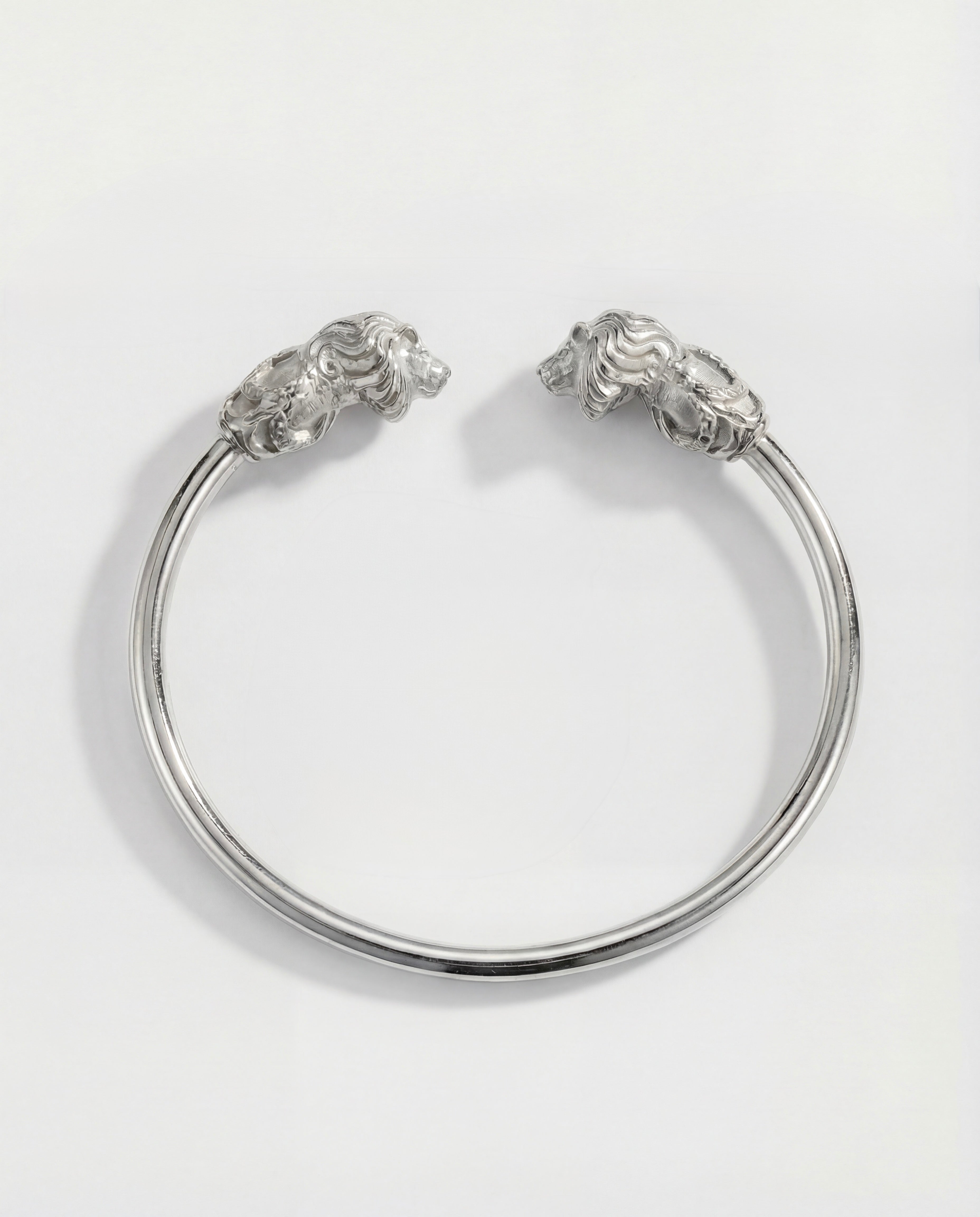 Silver bracelet with lion head designs on a white background