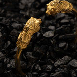 Gold bracelet with lion head designs on a dark textured background